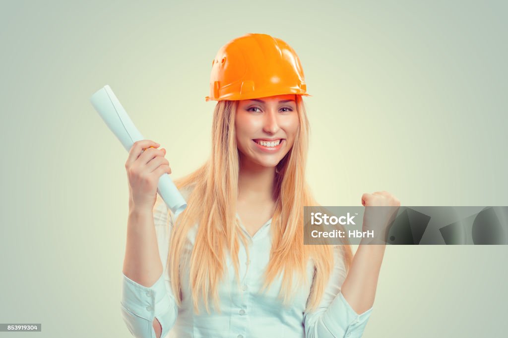 Architect successful. Closeup portrait happy smiling young construction woman yellow cap thumbs arm fist up celebrating win isolated green background. Positive human emotion facial expression attitude Adult Stock Photo