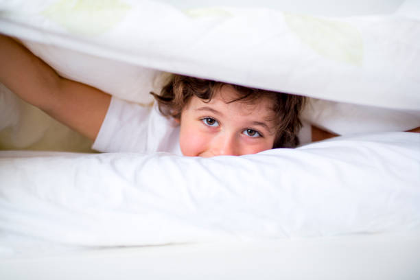 istock Adorable little boy in white t-shit lying in bed 853923214
