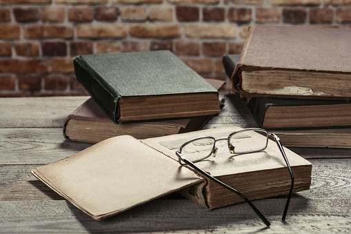 Vintage, antiquarian books pile on wooden surface