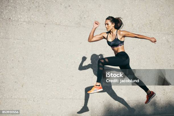 Foto de Ajuste A Jovem Mulher Pulando E Correndo e mais fotos de stock de Mulheres - Mulheres, Correr, Esporte