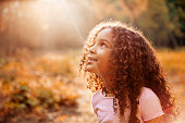 istock Afro american cute little girl with curly hair receives miracle sun rays from the sky 853930814