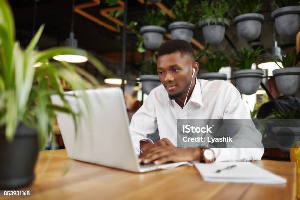 Man In Headphones Working At Laptop In Stylish Cafe Stock Photo - Download Image Now