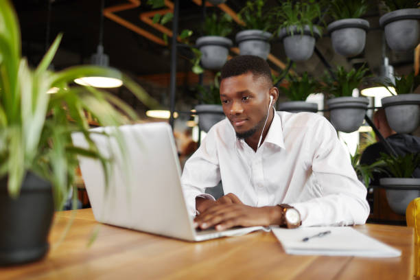 mężczyzna w słuchawkach pracujących na laptopie w stylowej kawiarni - touchpad computer using computer typing zdjęcia i obrazy z banku zdjęć