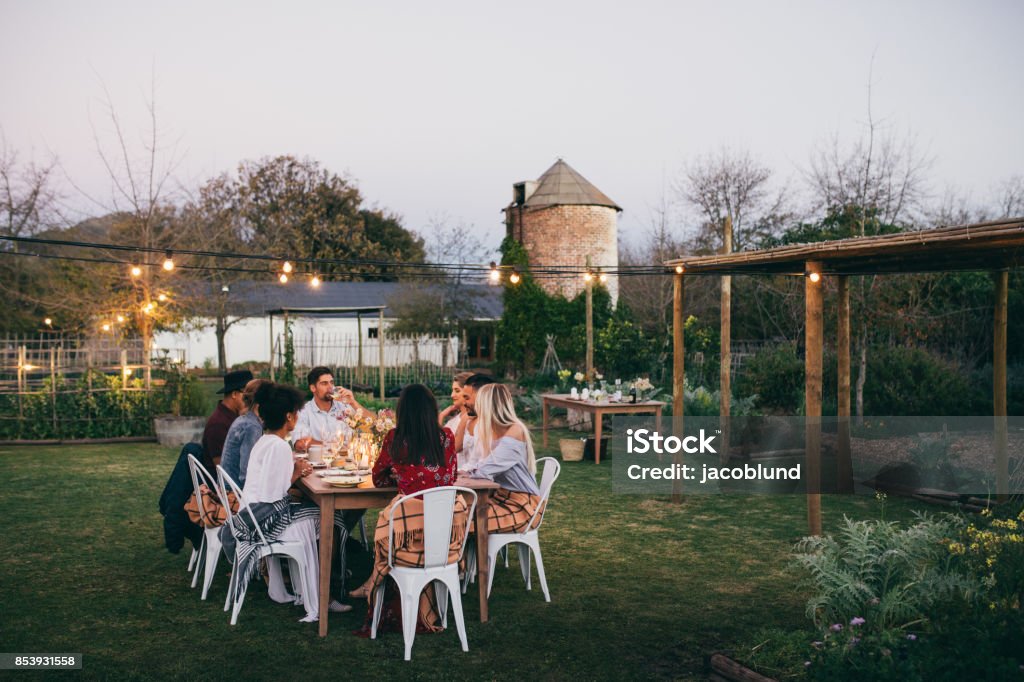 Group of men and women having outdoors party Group of men and women having outdoors party in restaurant. friends sitting around a table and having dinner. Yard - Grounds Stock Photo