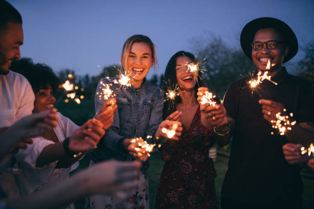 grupo de amigos disfrutando fuera con luces de bengala - sparkler fotografías e imágenes de stock