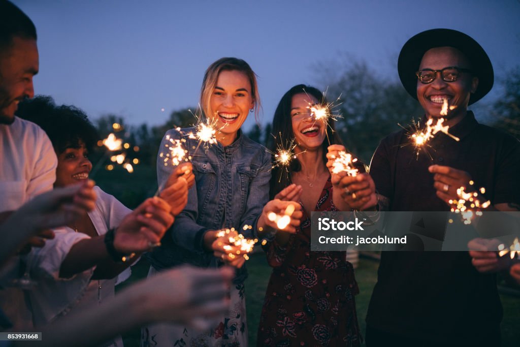 Group of friends enjoying out with sparklers Group of friends enjoying out with sparklers. Young men and women enjoying with fireworks. Firework Display Stock Photo