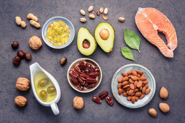Selection food sources of omega 3 and unsaturated fats. Superfood high vitamin e and dietary fiber for healthy food. Almond ,pecan,hazelnuts,walnuts,olive oil,fish oil and salmon on stone background. Selection food sources of omega 3 and unsaturated fats. Superfood high vitamin e and dietary fiber for healthy food. Almond ,pecan,hazelnuts,walnuts,olive oil,fish oil and salmon on stone background. fat nutrient stock pictures, royalty-free photos & images