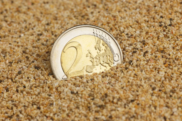 istock 2 euro coin buried in the sand 853935788