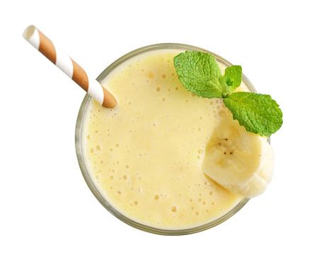Glass of banana milkshake or smoothie with drinking straw and mint leaves  isolated on white background, top view