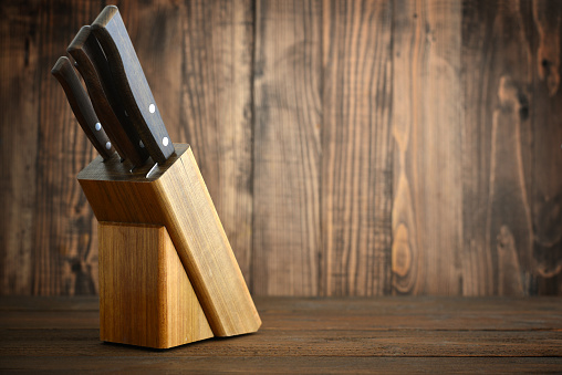 Knifes in wooden block on wooden background. (kitchen, knife, utensils)