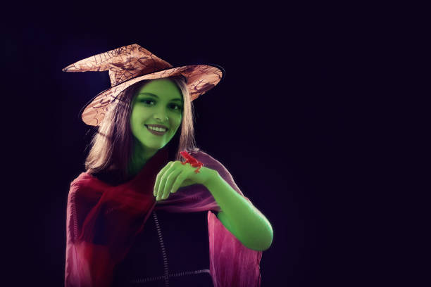 istock green  witch with red frog on black background 853938750