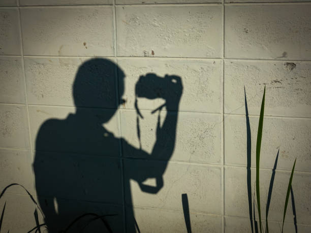 istock shadow of photographer take a photo on white bricks wall background 853939110