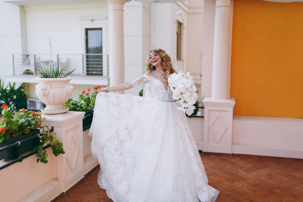 Beautiful curly blonde bride with a bouquet of flowers The beautiful curly blonde bride with a bouquet of flowers Milanova Bridal dress stock pictures, royalty-free photos  images
