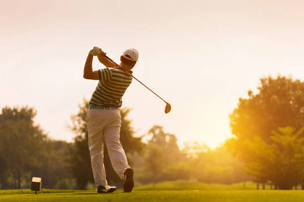 Golfers hit sweeping golf course in the summer Golfers hit sweeping golf course in the summer golfer stock pictures, royalty-free photos & images