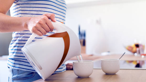 donna che prepara caffè o tè. versare acqua in una tazza. - pouring coffee human hand cup foto e immagini stock