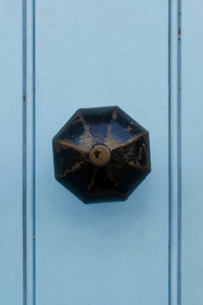Vintage brass doorknob with worn black paint on light blue wooden door Vintage brass doorknob with worn black paint on light blue wooden door blue front door stock pictures, royalty-free photos & images