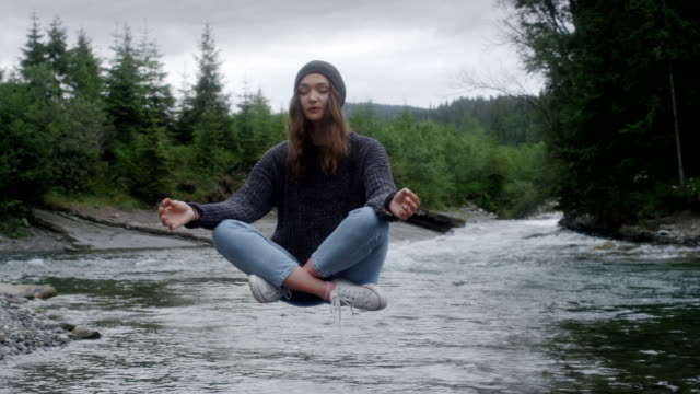 Magic in nature. Woman levitating above the stream