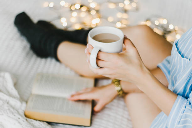 istock woman laying in bed and read book with cup if coffee. 853964396