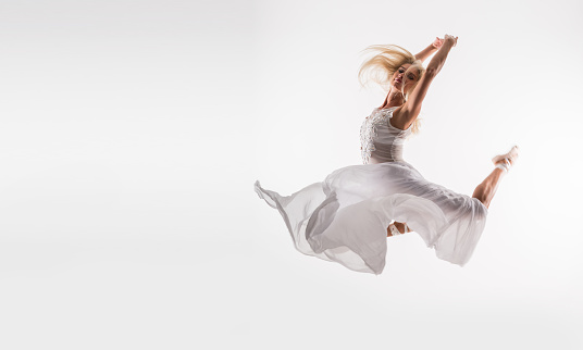 Young beautiful professional  ballet dancer over white background with white tulle