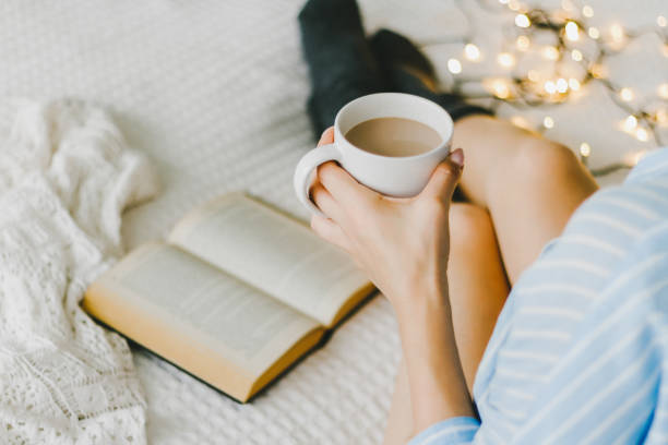 istock woman laying in bed and read book with cup if coffee. 853965184
