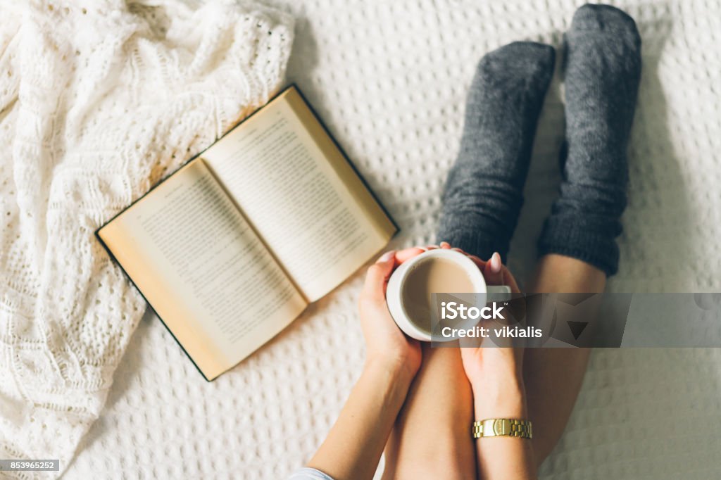 mujer acostado en la cama y leer libro con taza si café. - Foto de stock de Libro libre de derechos