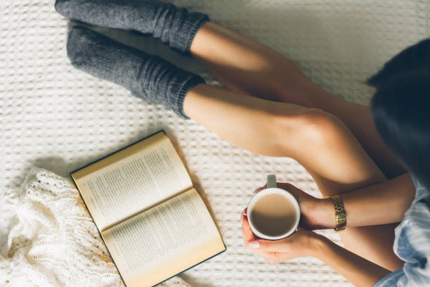istock woman laying in bed and read book with cup if coffee. 853965374