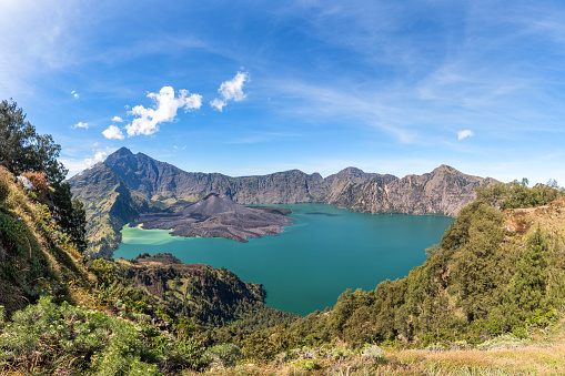 Panorama landscape of active volcano Baru Jari, Lake Segara Anak and summit of Rinjani mountain. Lombok island, Indonesia.