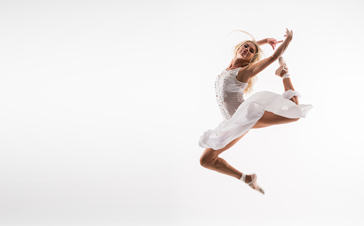 Young beautiful professional  ballet dancer over white background with white tulle