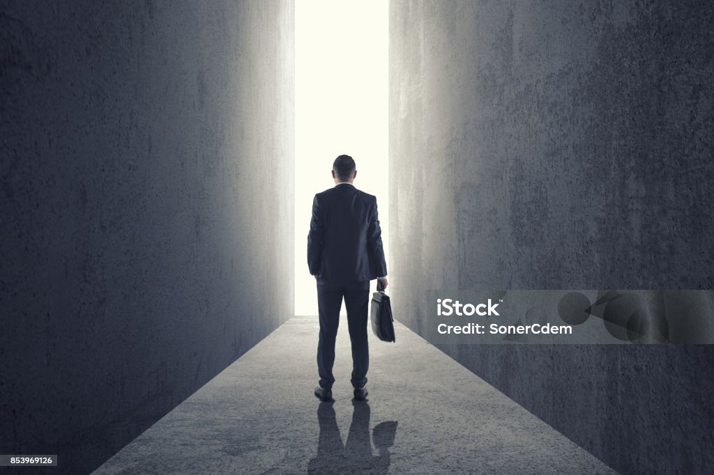 Silhouette of businessman entering giant doorway Silhouette of businessman entering giant doorway from dark room Leaving Stock Photo