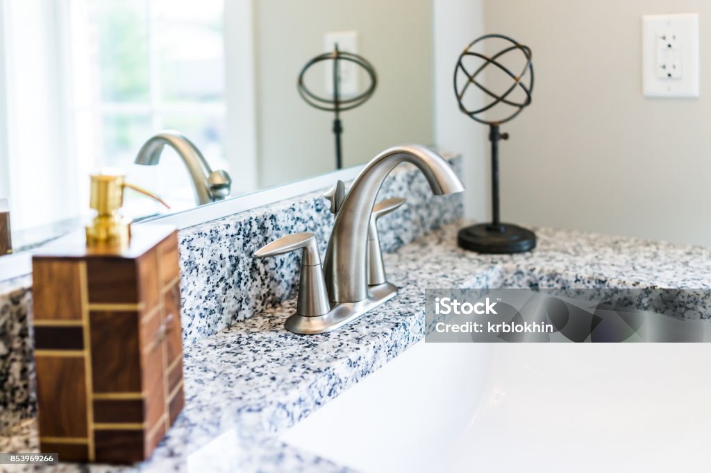 Closeup of modern bathroom sink with granite countertop, mirror, soap dispenser pump and faucet in staging model home, apartment or house Bathroom Stock Photo
