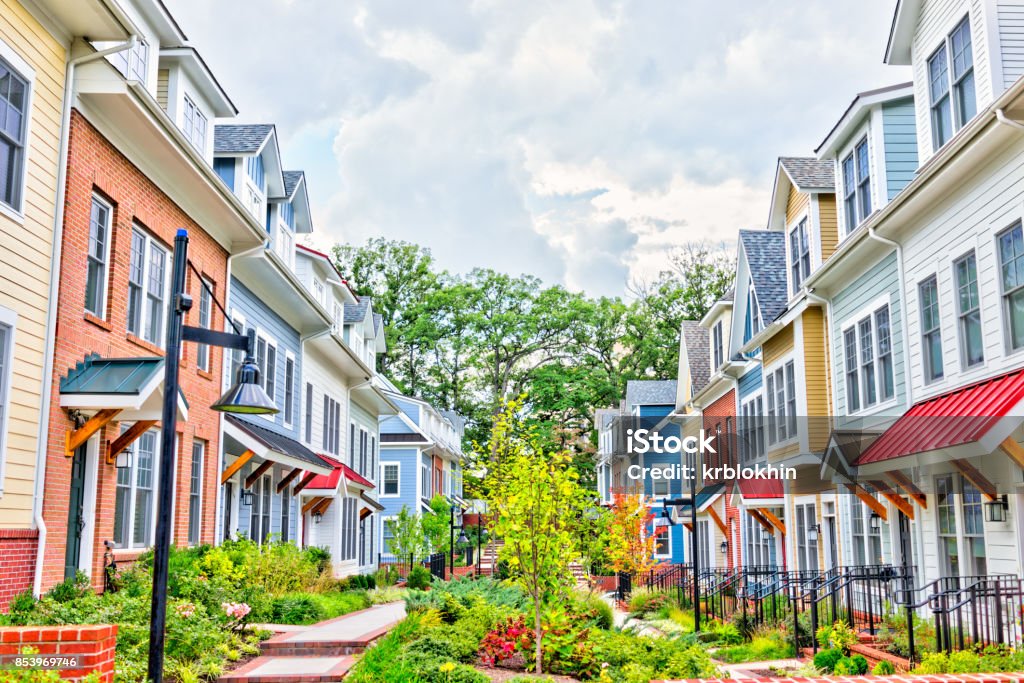 Row of colorful residential townhouses Row of colorful, red, yellow, blue, white, green painted residential townhouses, homes, houses with brick patio gardens in summer Maryland - US State Stock Photo