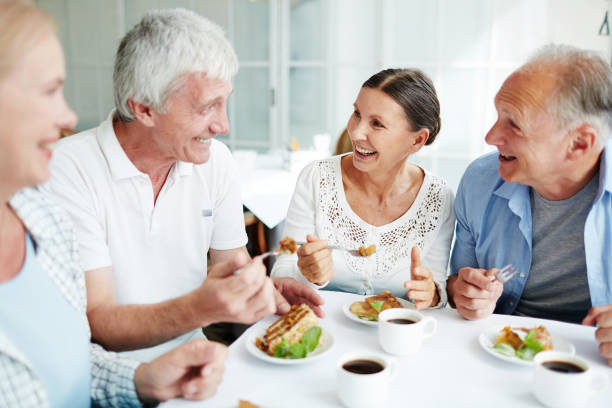 Conversation by dessert Cheerful senior friends having tasty dessert and talking in cafe dining stock pictures, royalty-free photos & images