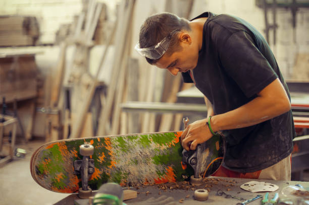 istock Young man in carpentry workshop fixing wheel on his skateboard 853972542
