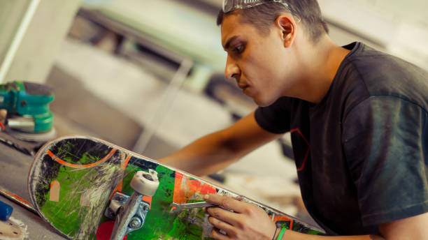 istock Young man in carpentry workshop fixing wheel on his skateboard 853972830