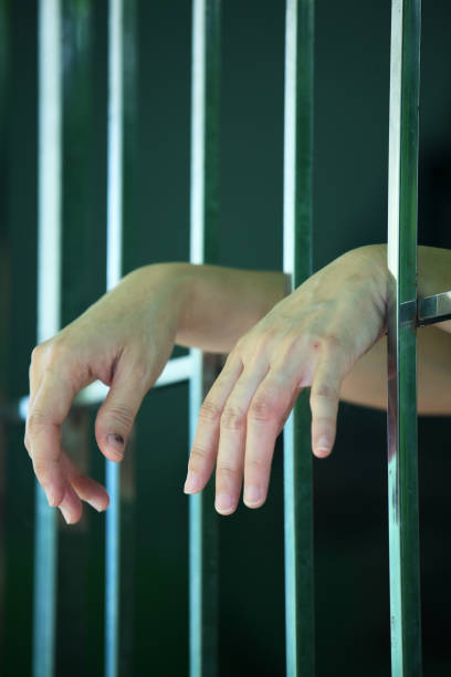 istock hands of prisoner in jail as background. 853977250