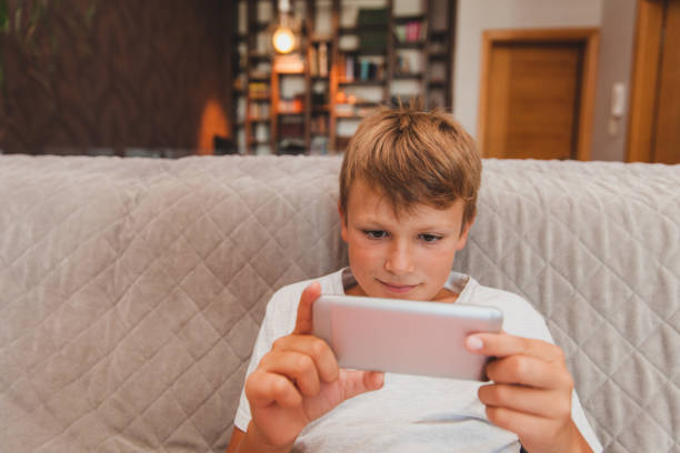 istock Young Boy Playing Games on Smart Phone 853978120