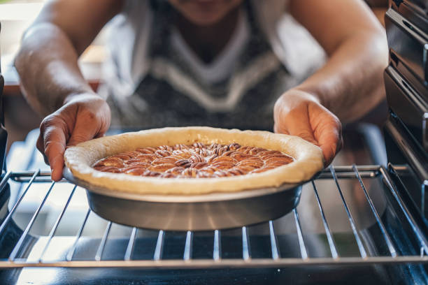выпечка пекан пирог в духовке для праздников - cooking thanksgiving women baking стоковые фото и изображения