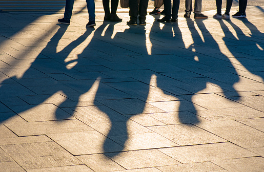 Shadows and silhouettes of people at a city during sunset