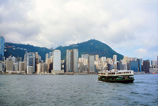Historic photo of the British Colonial Hong Kong, 1989. The view of the city skyline of the island of Hong Kong, the Victoria Harbor, the Central District, the Victoria Peak from the Star Ferry Terminal in the Kowloon peninsula.