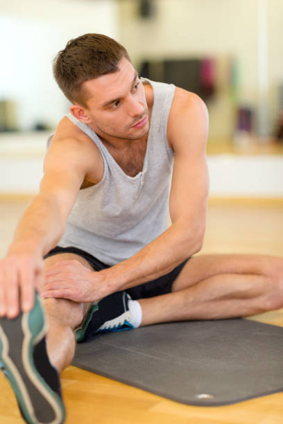 istock serious man stretching on mat in the gym 854010166