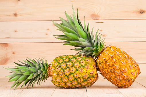 Couple of ripe pineapples. Located on a wooden background. Close-up.