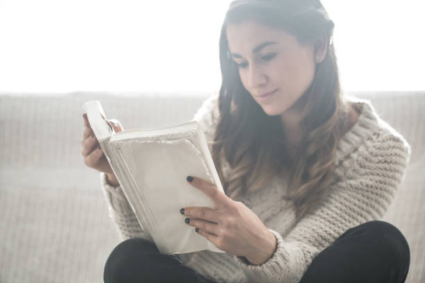 istock girl reading a book closeup on the sofa 854018326