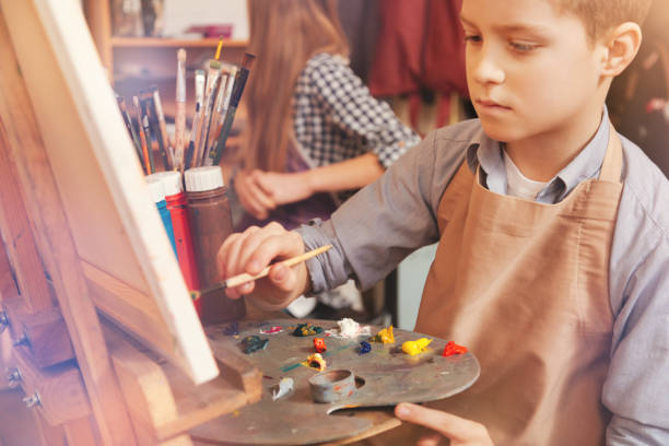 istock Serious young boy painting on art canvas 854024228