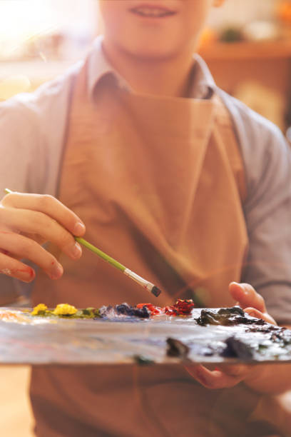 istock Scaled up look on boy holding palette with oil paints 854025182