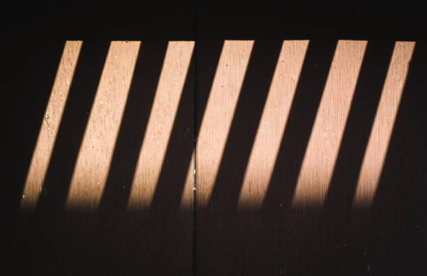 istock shade from wooden lath window which causes shadow and light to wood floor. 854032340