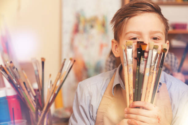 istock Funny teenage boy playing with brushes while posing for camera 854032354