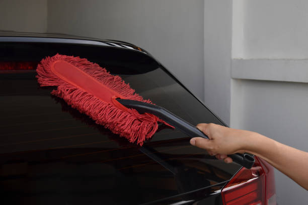 asian male hand about 40 years old holding a red dust brush. clean black car. - domestic car color image horizontal car imagens e fotografias de stock