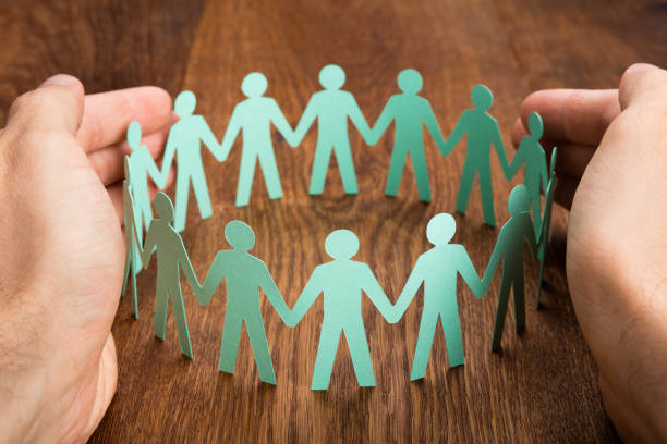 istock Person Protecting Cut-out Figures On Desk 854044898