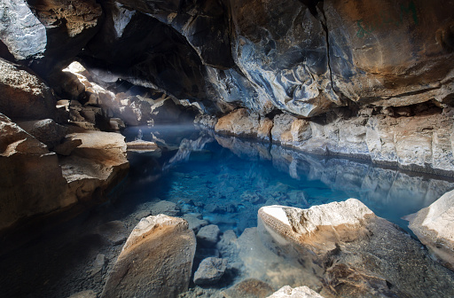 The famous cave grjotagja in iceland with bright blue water . Geothermal cave with hot water.