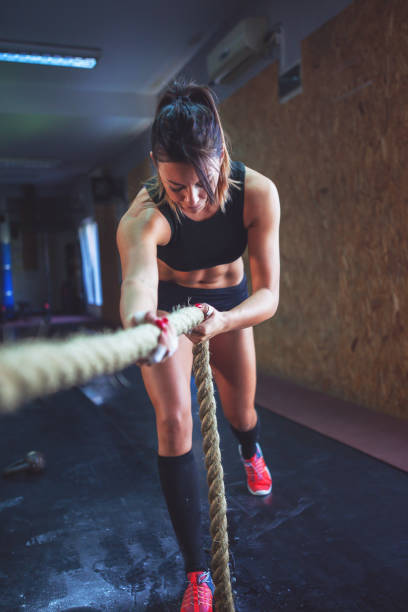 istock Strong young woman pulling rope at a gym 854056372